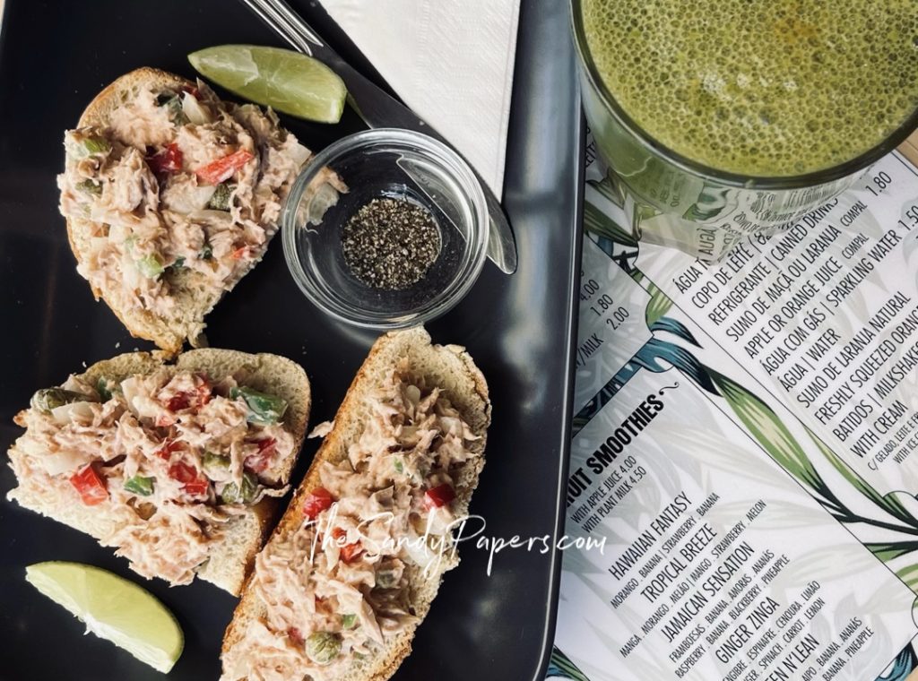Toasted bread slices topped with creamy chicken salad and garnished with lime and pepper.